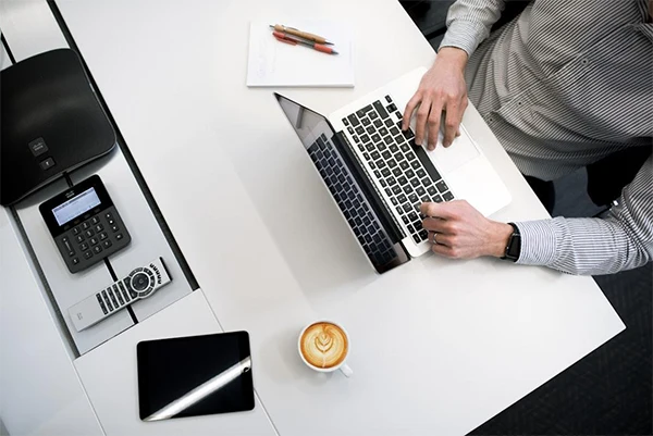 A person reviewing financial documents at a desk with a laptop